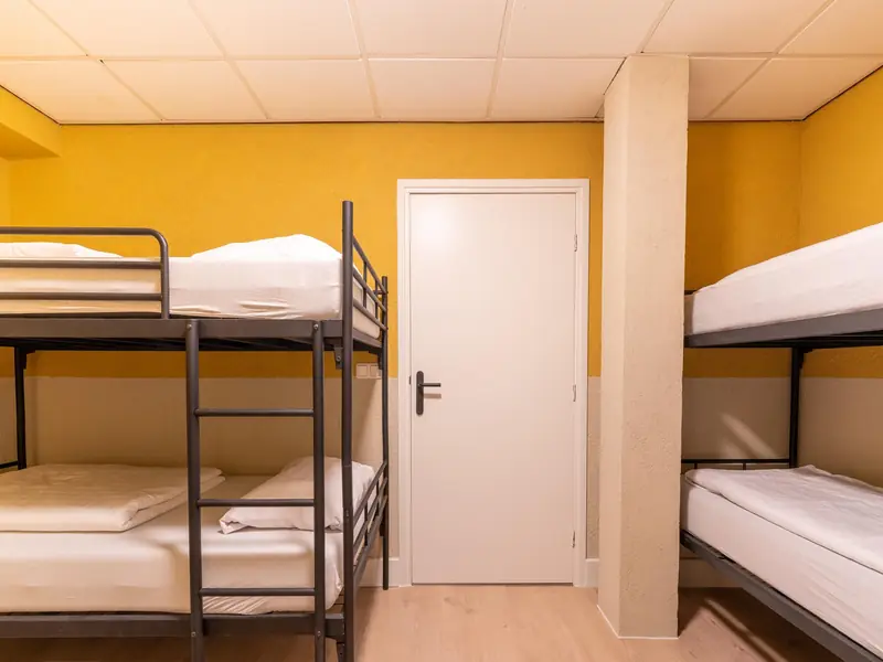 Bedroom with two black metal bunk beds and yellow walls around a white door.
